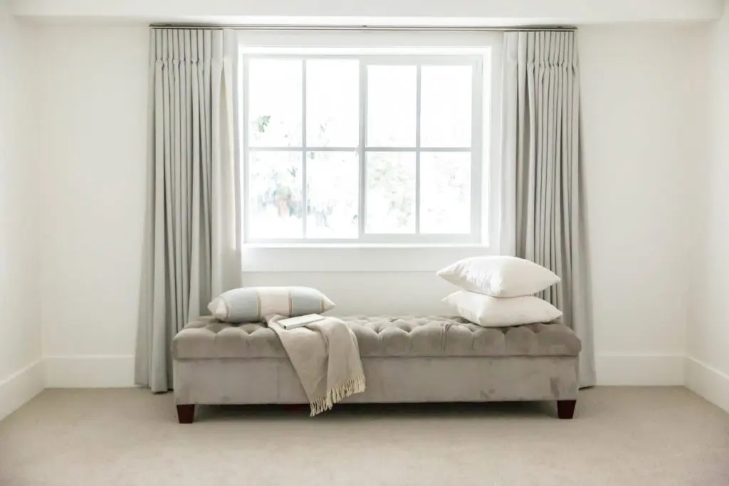 cushioned bench in front of window with drapes